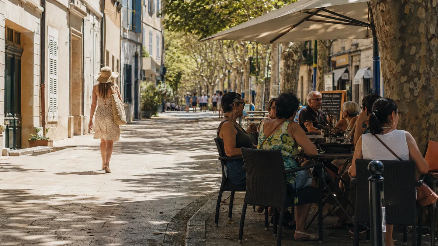 Rue française très ensoleillée avec terrasses de café et passants à l’ombre