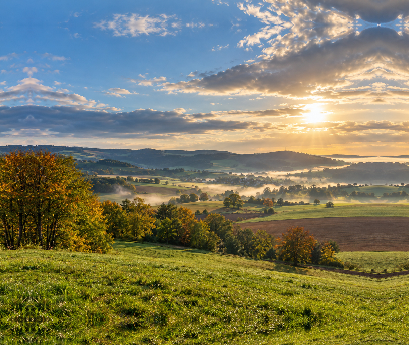 Paysage rural d’automne baigné de soleil avec brumes matinales, image d’illustration pour la météo en France.